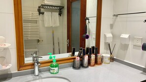 A bathroom with a sink, mirror, towel rack, and various toiletries. - Beijing CBD - Studio Apartment Queenbeds (Beijing)