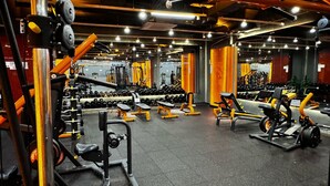 Ein Fitnessstudio mit unterschiedlichen Trainingsgeräten, Gewichtsständern und Bänken.