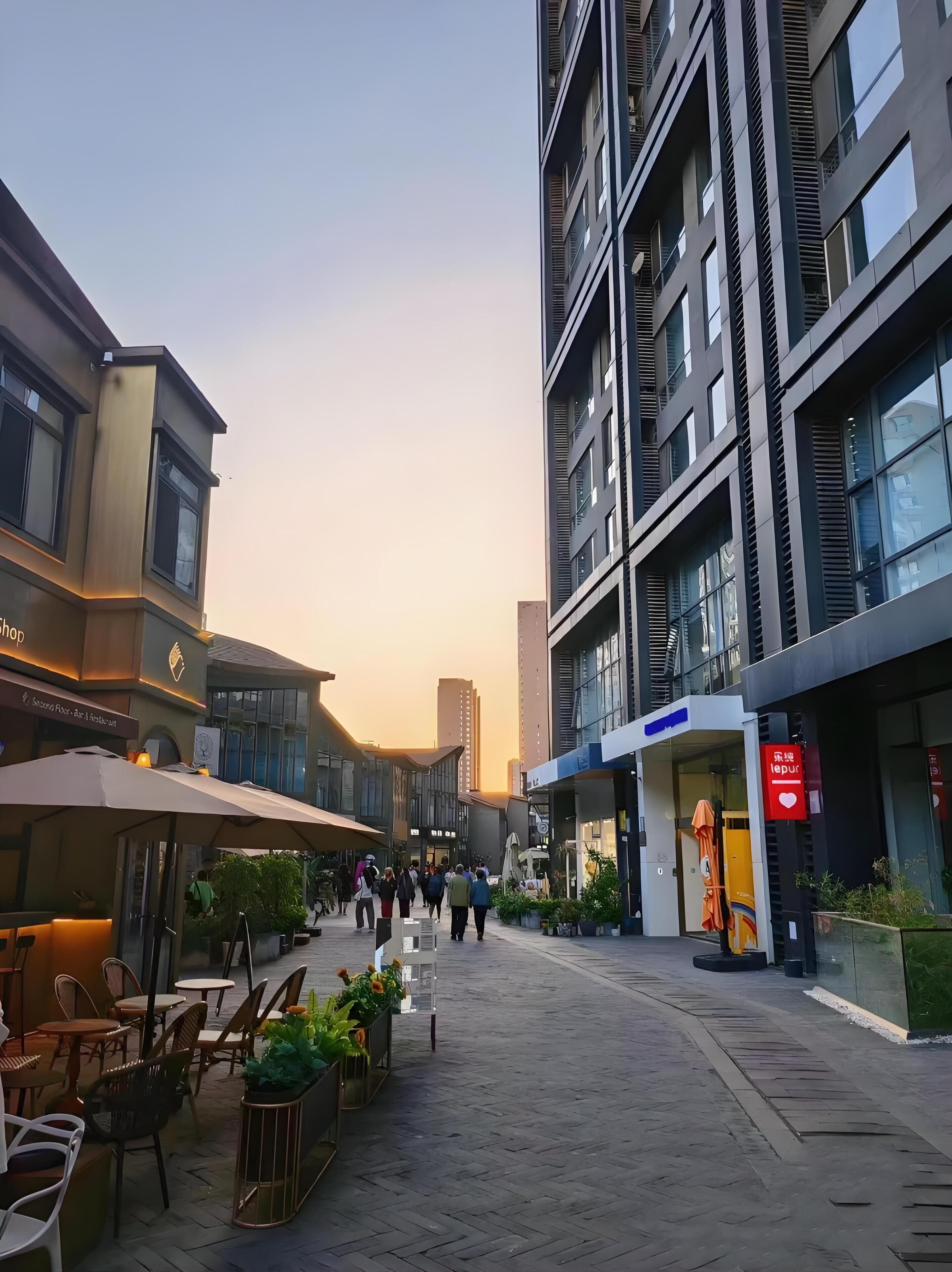 A modern urban street with a café on the left and a building with a sign reading "lepur" on the right.