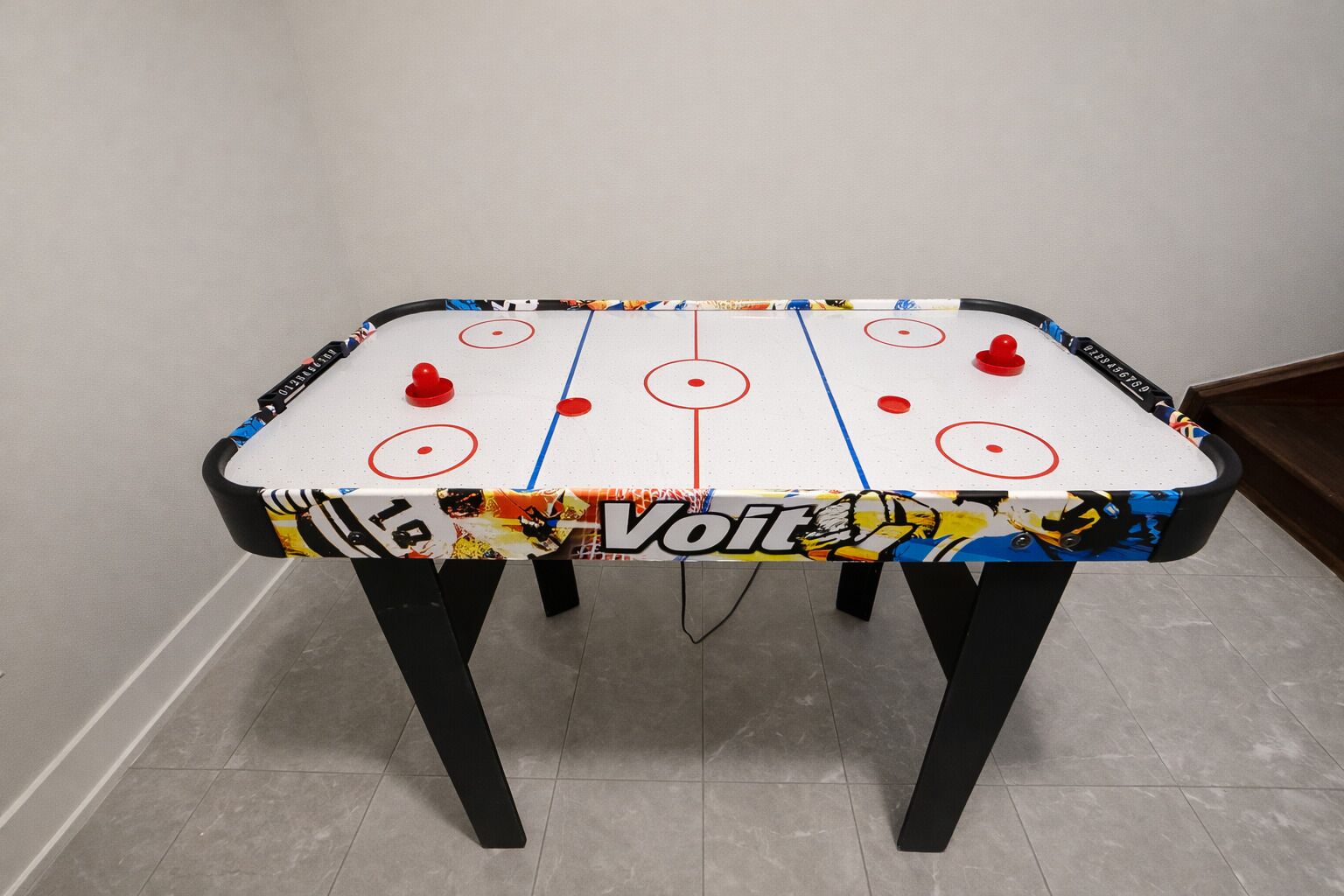 A table football game with a colorful table cover and black legs.