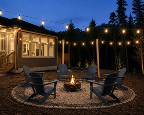 Ein Haus mit Terrasse, Sitzgelegenheiten im Freien und einem Feuerkorb.