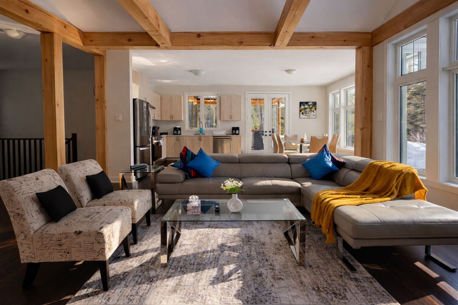 A modern living room with a sectional sofa, a glass coffee table, and a dining area visible through an open door.