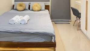 A modern bedroom with a bed, grey curtains, a ceiling light, and a small desk with a chair. - Orchids @ Shore Residences 1BR Pool Access (Pasay City)
