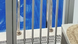 A swimming pool with a white railing, surrounded by a modern building with balconies. - Orchids @ Shore Residences 1BR Pool Access (Pasay City)