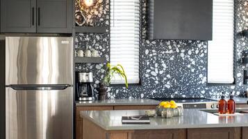 Una cocina moderna con una isla central, electrodomésticos de acero inoxidable y una salpicadera con diseño moteado.