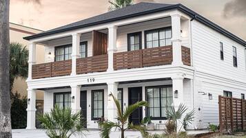 A two-story house with a balcony, large windows, and a number '119' displayed on the front.