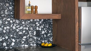 Una cocina con salpicadero de granito, armarios de madera, un refrigerador de acero inoxidable y una estufa a gas.