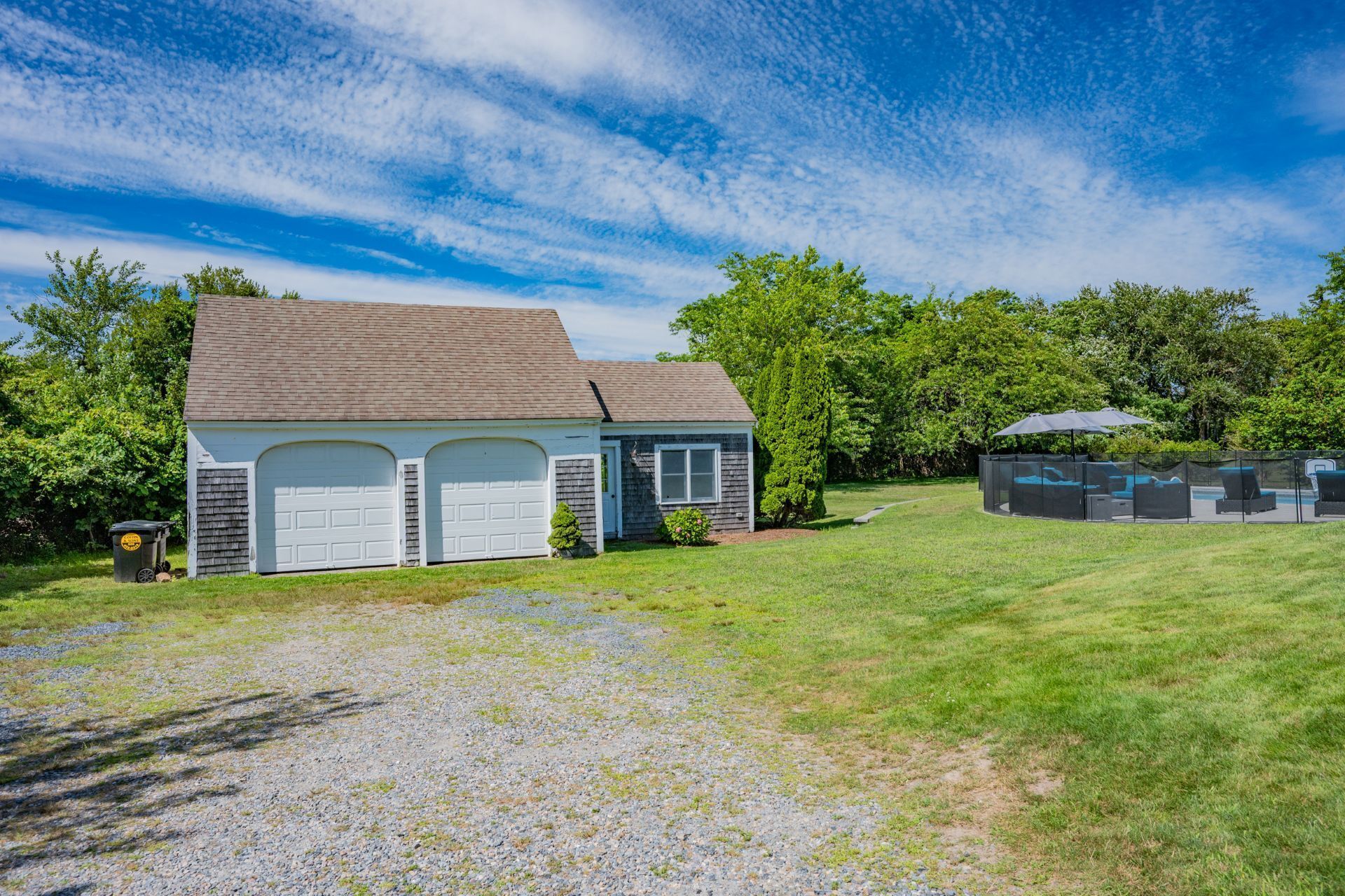 A two-story house with a garage, a covered outdoor seating area, and a well-maintained lawn.