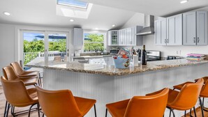 Una cucina moderna con una grande isola, mobili bianchi e vista sul verde circostante.