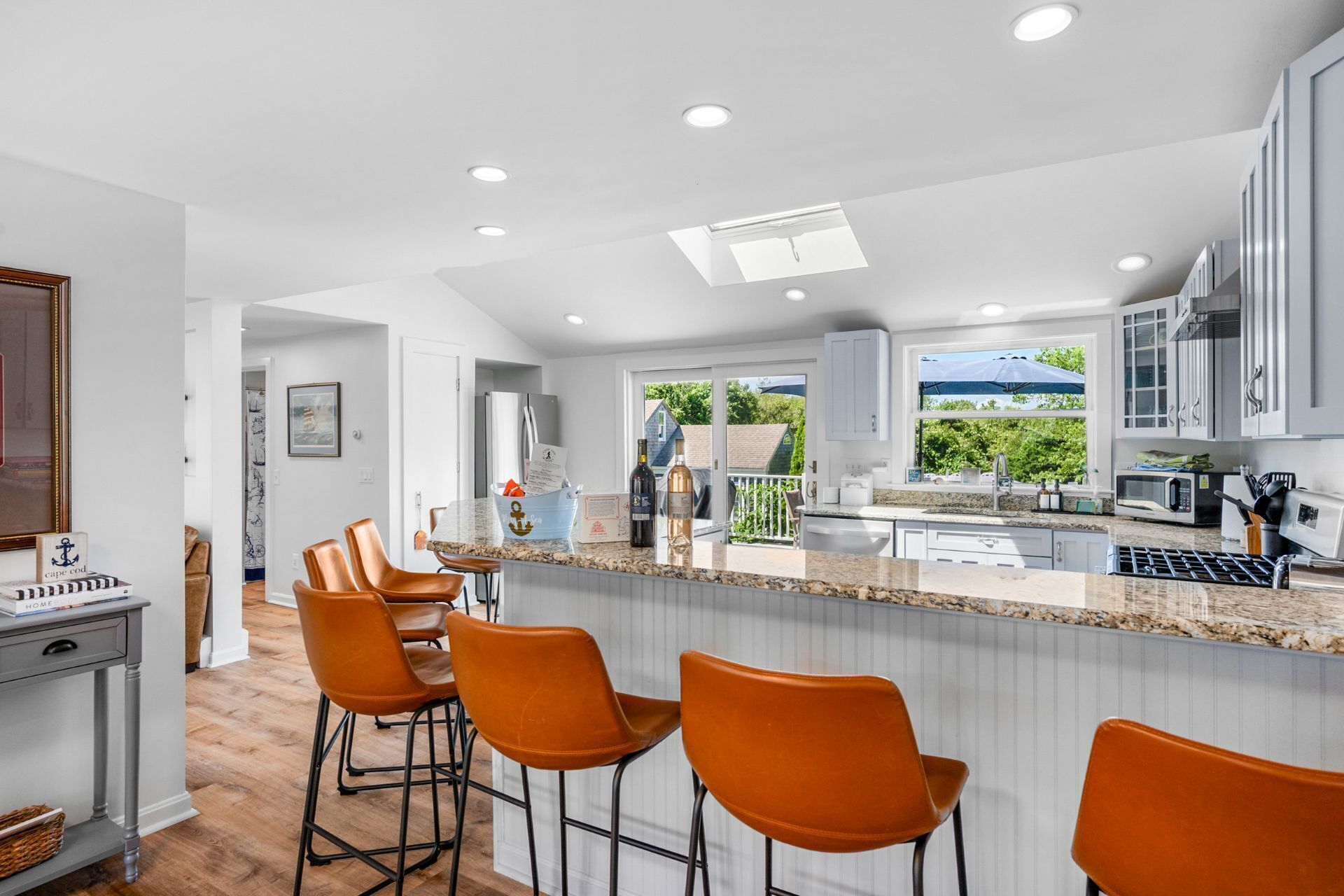 A modern kitchen with a central island, bar stools, and a view of the outdoors.