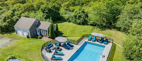 En boligejendom med swimmingpool, udendørs siddepladser og et hus.