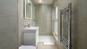 Een moderne badkamer met een wit wastafelmeubel, spiegel en douche.