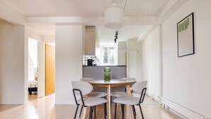 Un espace repas moderne avec une table ronde, quatre chaises et un luminaire suspendu.