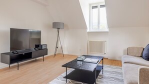 Un salon moderne avec un téléviseur à écran plat, une lampe sur pied, un canapé et une table basse.