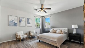 A bedroom with a large bed, two chairs, a nightstand, and a ceiling fan. - Charming 2-bedroom townhome near ASU in Tempe  with AC, garage, and a pool! (Tempe)