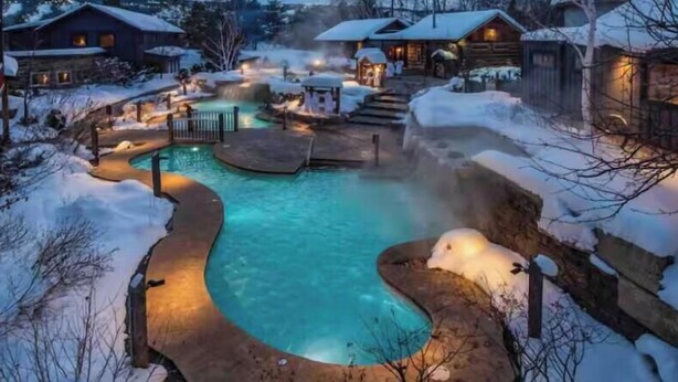 A winter scene with a pool area surrounded by snow-covered ground and buildings. - 20 minutes to Blue Mountain / games room (Wasaga Beach)