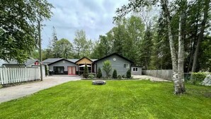 A residential property with a well-maintained lawn, a small pond, and a wooden fence. - 20 minutes to Blue Mountain / games room (Wasaga Beach)