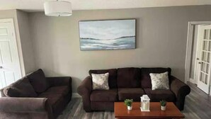 A living room with two sofas, a coffee table, and a painting on the wall. - 20 minutes to Blue Mountain / games room (Wasaga Beach)