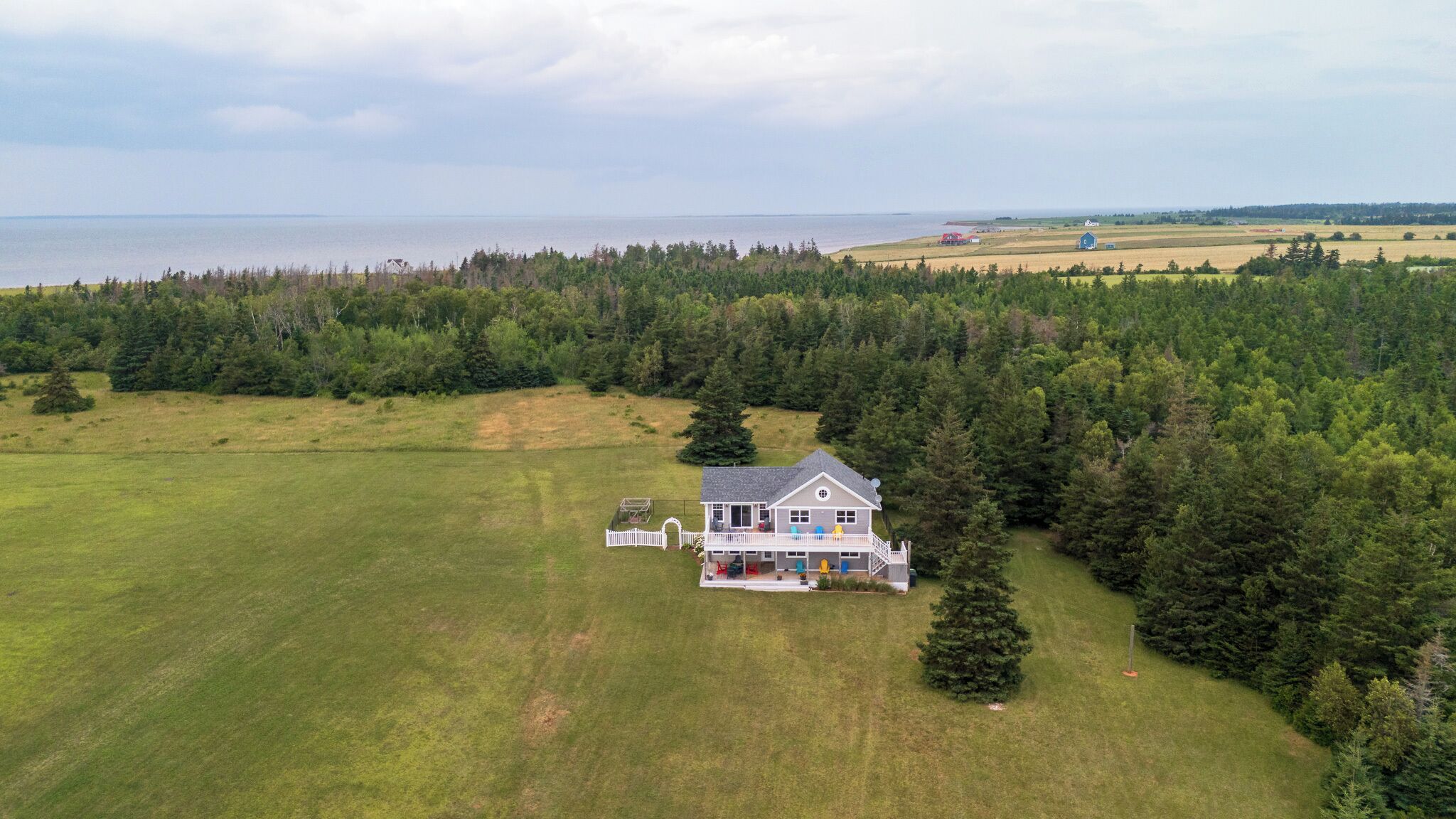 Une grande maison avec une vaste pelouse et une vue sur la mer.