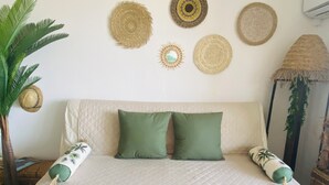 A bed with a quilted cover, two green pillows, and decorative woven items on the wall.