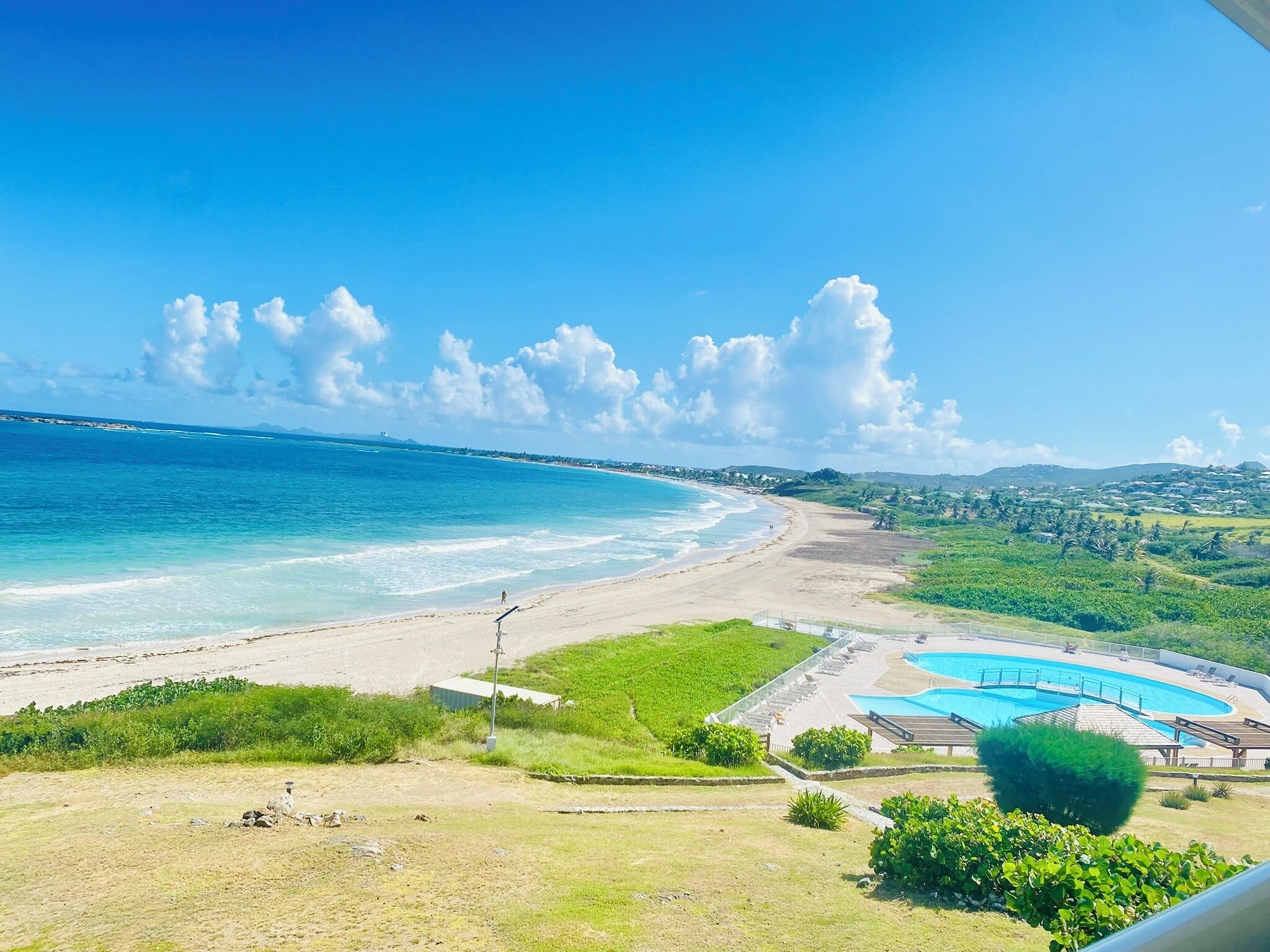 A beach with a swimming pool and a view of the ocean.