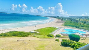 A beach with a swimming pool and a view of the ocean.
