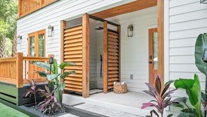 Une maison avec une terrasse en bois, un porche couvert et une porte d’entrée.