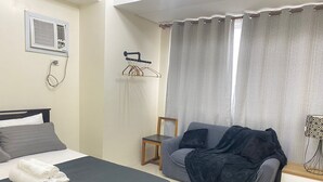 A bedroom with a bed, a small table, a chair, and a sofa. - Lavender @ Shore Residences 2BR (Pasay City)