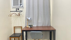 A small, neatly arranged room with a desk, chair, and a window with a patterned curtain. - Lavender @ Shore Residences 2BR (Pasay City)