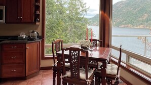 A kitchen with wooden cabinets, a dining table with chairs, a skylight, and a view of a lake and mountains.