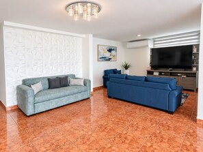 A modern living room with a sectional sofa, a smaller sofa, a flat-screen TV, and a decorative wall panel. - Luquillo Oasis
(Luquillo)