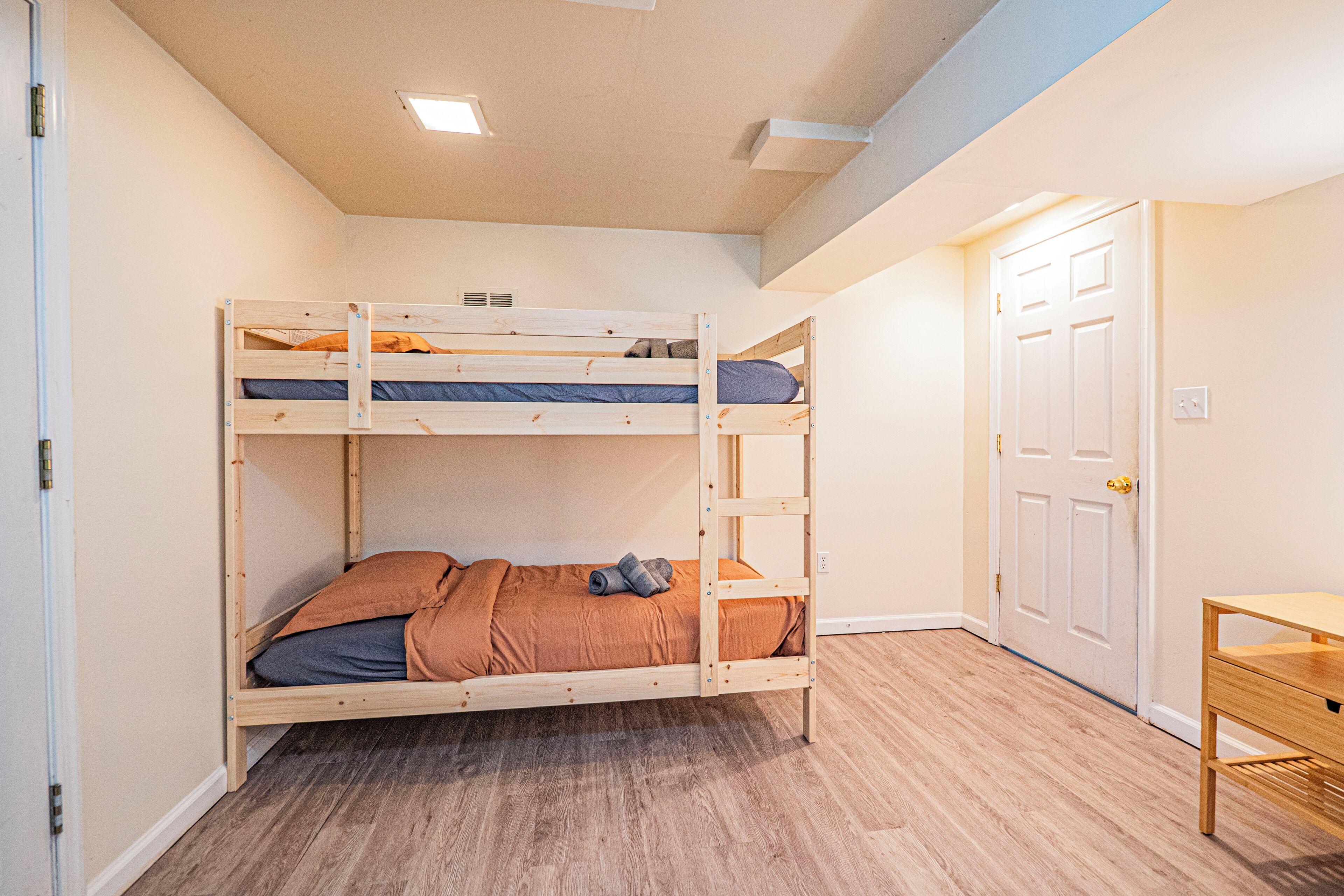A bunk bed room with a wooden desk and a white door.