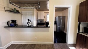 Una cocina compacta con horno integrado, un refrigerador de acero inoxidable y una cafetera sobre la encimera.