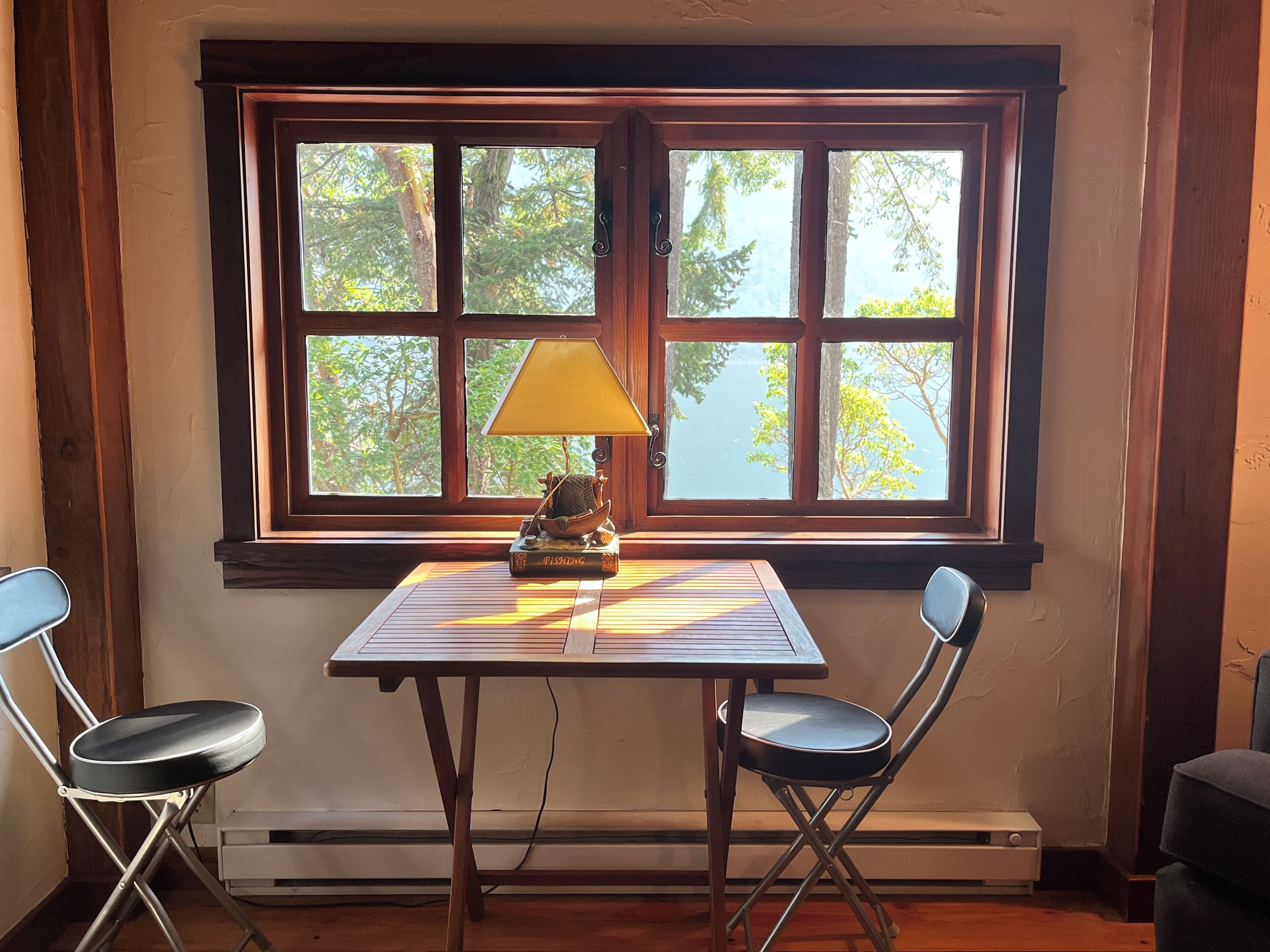 Une pièce avec une table et deux chaises, une lampe et un livre intitulé « PÊCHE » posé sur la table.