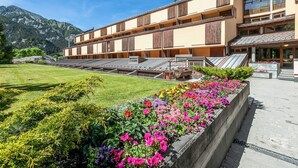 Un hôtel à l’architecture imposante, avec plusieurs étages, une pelouse bien entretenue et de magnifiques parterres de fleurs aux couleurs vives.