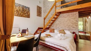 Une chambre avec un escalier à la manière d’un loft, un coin repas avec une table dressée pour deux personnes, et des œuvres d’art accrochées aux murs.