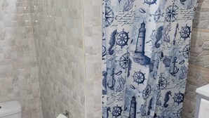 A bathroom with a nautical-themed shower curtain, a toilet, and a bidet. - J and N Cozy Quarters (Roseau)