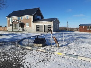 Un immeuble résidentiel doté d’un garage, d’un espace extérieur couvert et d’un terrain enneigé.