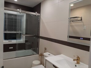 Une salle de bain moderne avec une douche en verre, un lavabo blanc et un miroir au-dessus du lavabo.