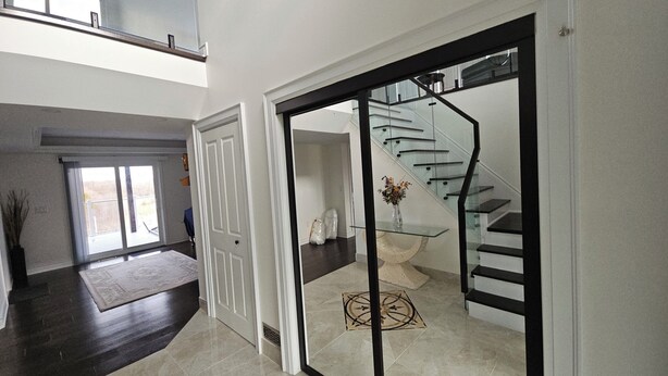 Ein modernes Interieur mit Treppe, einer Tür zu einem anderen Raum und Blick ins Freie.
