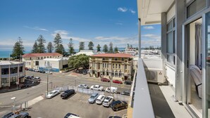 A view of a parking lot with several cars, a building with a red roof, and a clear blue sky. - Art Deco Escape - Inner City Apartment Napier (Napier)