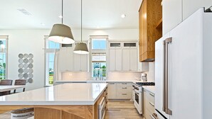 A modern kitchen with a large island, wooden cabinets, and stainless steel appliances.