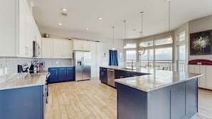 A spacious kitchen with a large island, modern appliances, and a view to the outside. - Stunning bay front home with fishing pier, large deck, & private pool (Rockport)