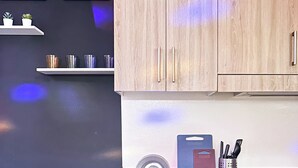 A dining table set with plates, bowls, and glasses, with chairs on one side and kitchen cabinets in the background. - Granite @ Shore Residences 2BR (Pasay City)