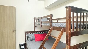 A bunk bed with a wooden frame and gray bedding, a wooden door, and a trash bin. - Granite @ Shore Residences 2BR (Pasay City)