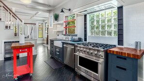 A modern kitchen with a gas stove, stainless steel appliances, and a red cart. - Stunning Home in South Highland (Shreveport)