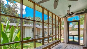 A covered outdoor area with a ceiling fan, wooden deck, and a view of a backyard with a pool. - Stunning Home in South Highland (Shreveport)