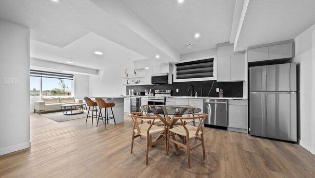 Una cocina moderna con comedor, que presenta una mesa redonda de vidrio y sillas de madera.