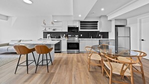 Una cocina moderna con armarios blancos, electrodomésticos de acero inoxidable y una mesa de comedor de vidrio.