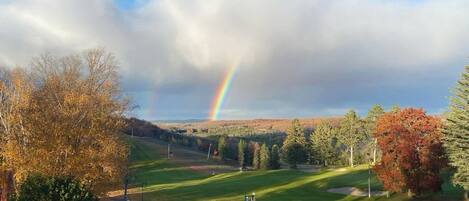Un campo de golf con un arcoíris, árboles y cielo despejado.